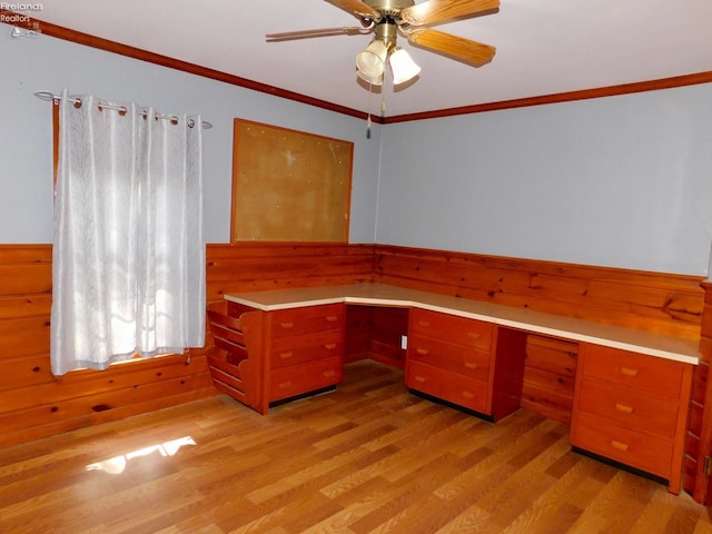 unfurnished office with ornamental molding, built in desk, light hardwood / wood-style flooring, and ceiling fan