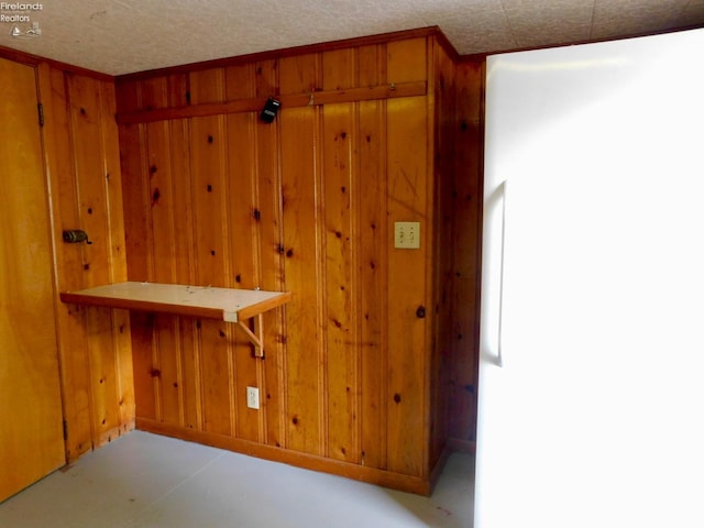 interior space with a textured ceiling and wood walls