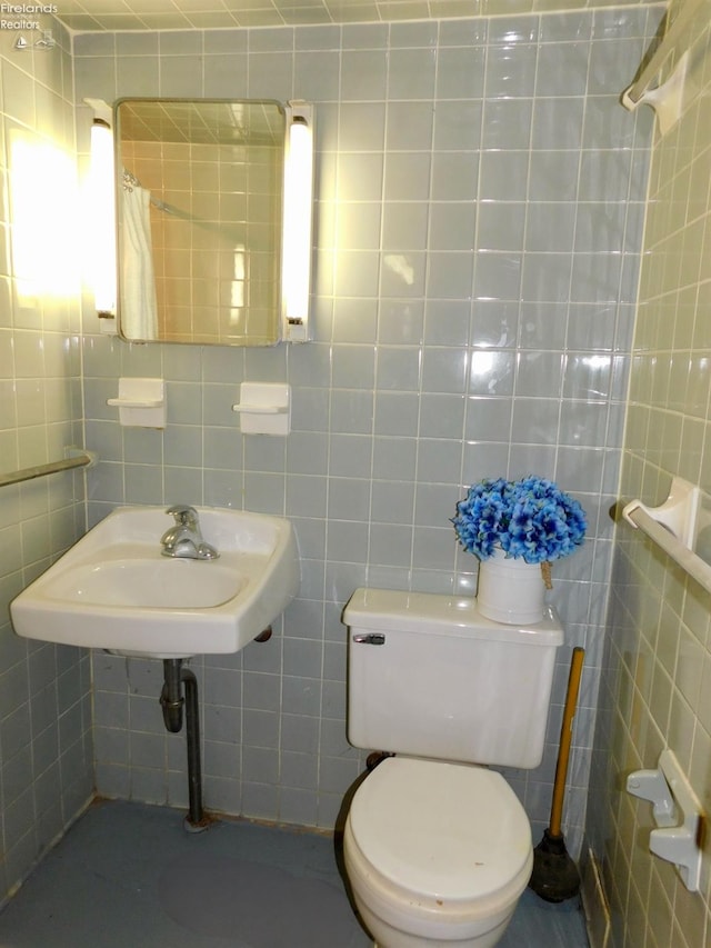 bathroom with tile walls, toilet, and sink