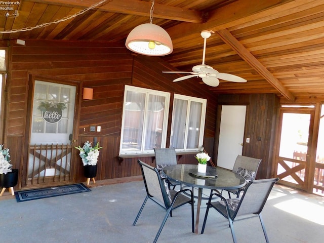 interior space with ceiling fan, wood walls, wooden ceiling, and lofted ceiling with beams