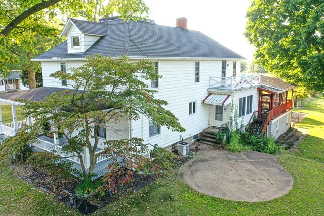 rear view of property with cooling unit, a yard, and a patio area