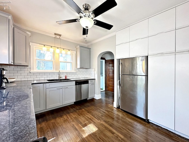 kitchen with ornamental molding, dark hardwood / wood-style flooring, sink, ceiling fan, and appliances with stainless steel finishes