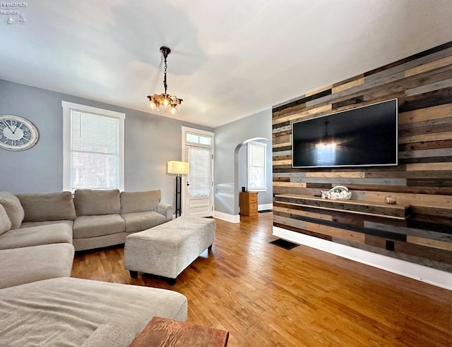 living room featuring hardwood / wood-style flooring, wood walls, and a notable chandelier