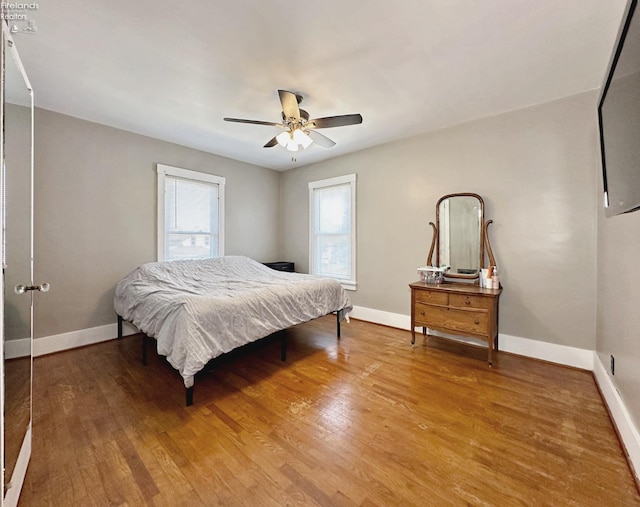 bedroom featuring multiple windows, hardwood / wood-style floors, and ceiling fan