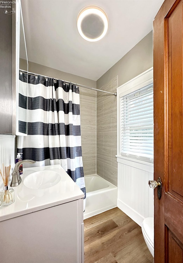 full bathroom with vanity, toilet, hardwood / wood-style floors, and shower / bath combo with shower curtain