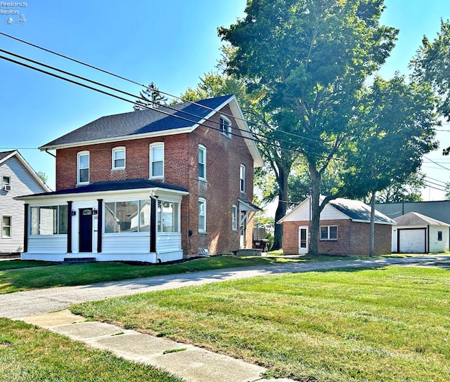 view of front of home featuring a garage, a front lawn, and an outbuilding