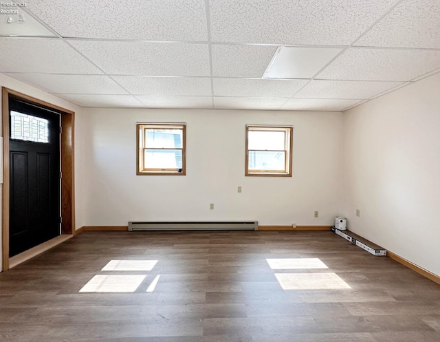 interior space featuring wood-type flooring, baseboard heating, and a drop ceiling