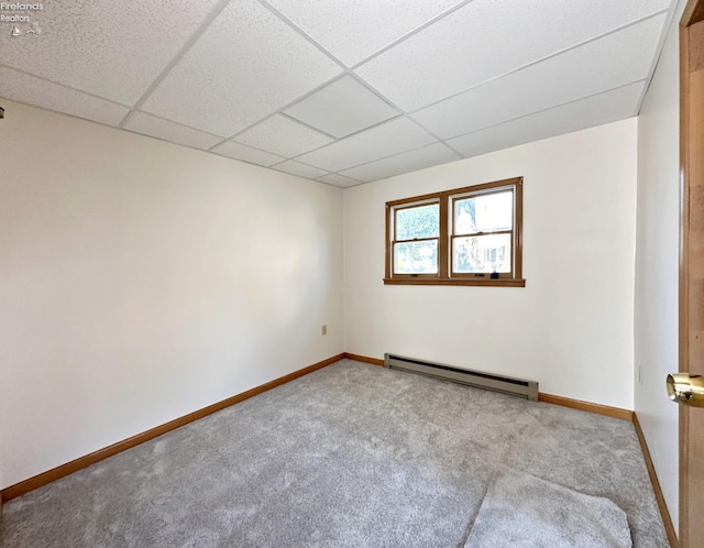 carpeted spare room with a baseboard heating unit and a drop ceiling