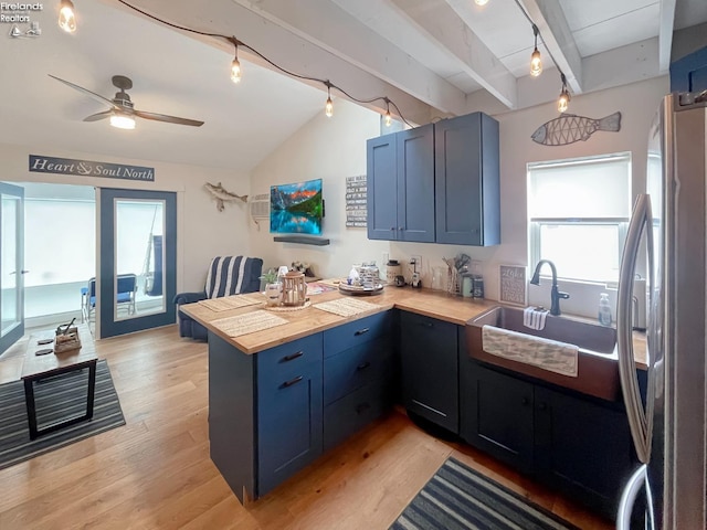 kitchen featuring wood counters, sink, light wood-type flooring, blue cabinetry, and stainless steel refrigerator