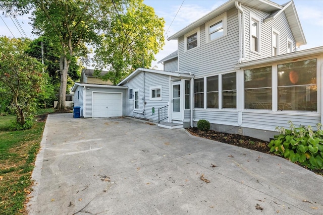 view of home's exterior with a garage, an outdoor structure, and a sunroom