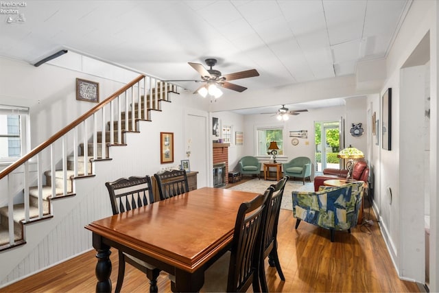 dining room with a healthy amount of sunlight, ceiling fan, hardwood / wood-style flooring, and a fireplace