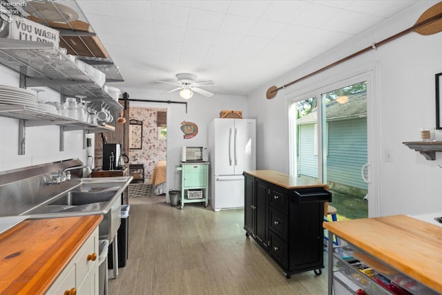 kitchen featuring dark wood-type flooring, white cabinetry, a barn door, ceiling fan, and white refrigerator