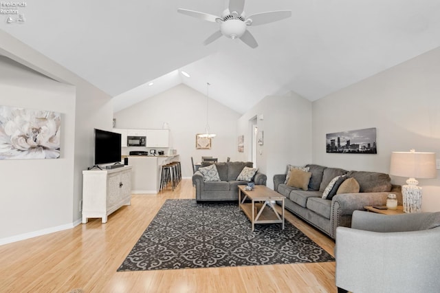 living room featuring lofted ceiling, ceiling fan, and light hardwood / wood-style floors