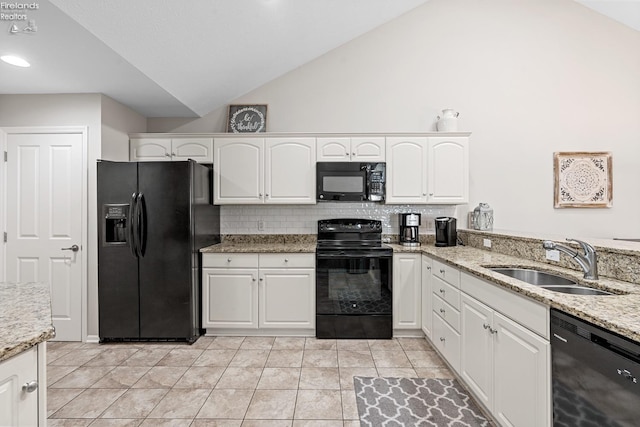 kitchen with black appliances, sink, lofted ceiling, light stone counters, and white cabinets