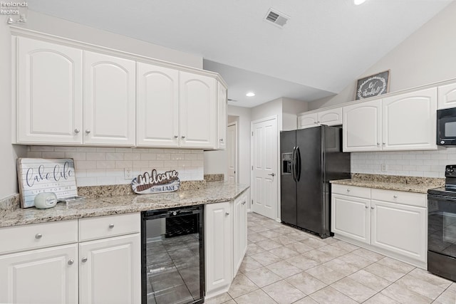 kitchen featuring vaulted ceiling, light stone counters, white cabinetry, black appliances, and beverage cooler