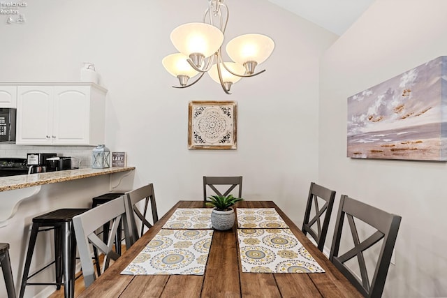 dining space featuring dark wood-type flooring, lofted ceiling, and an inviting chandelier