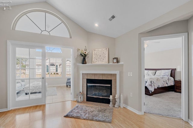 living room with vaulted ceiling, wood-type flooring, ceiling fan, and a tile fireplace