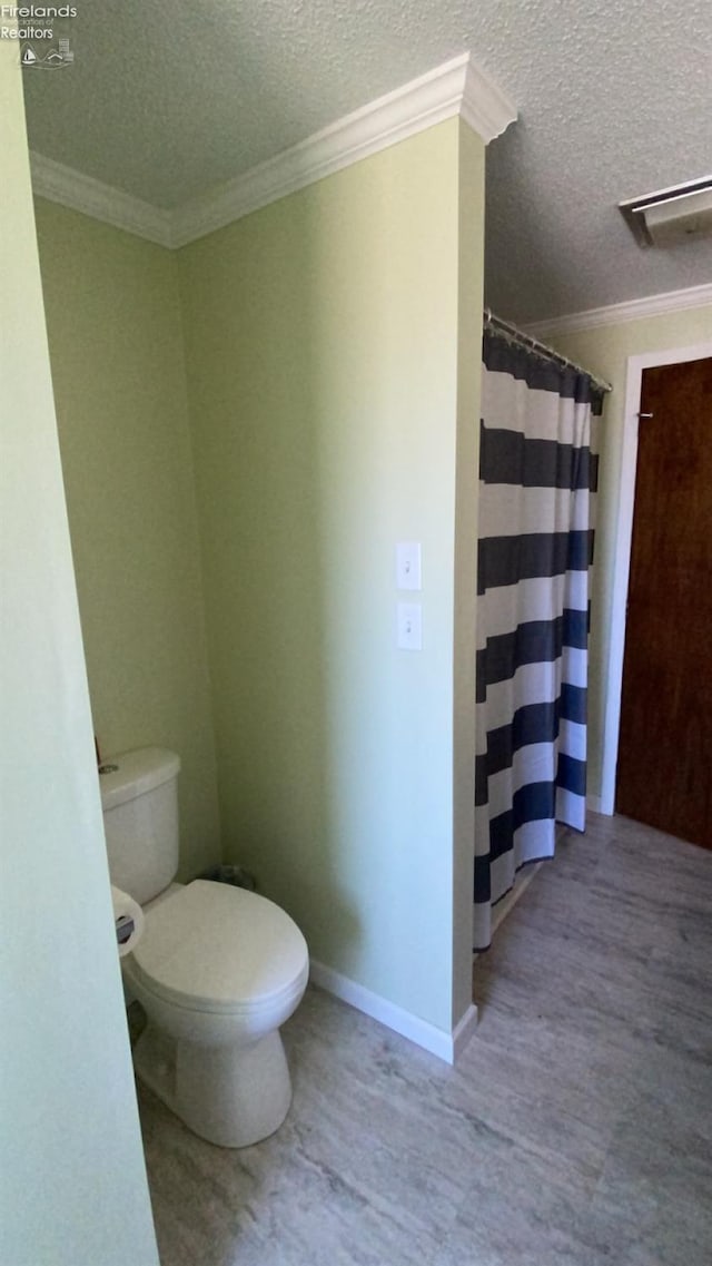 bathroom with wood-type flooring, ornamental molding, a textured ceiling, and toilet