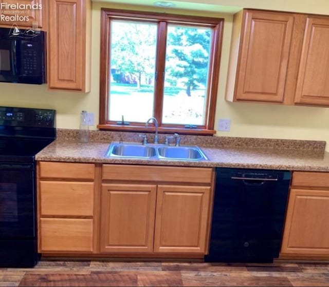 kitchen featuring a wealth of natural light, black appliances, dark wood-type flooring, and sink