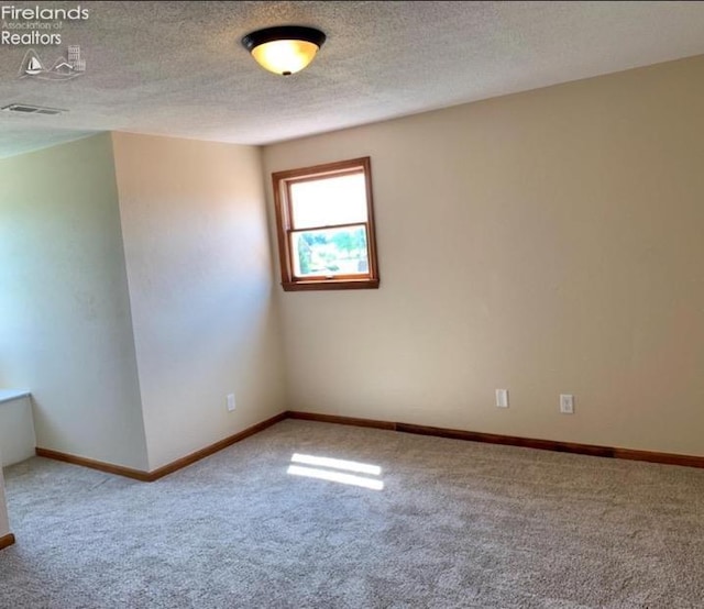 empty room featuring a textured ceiling and carpet flooring