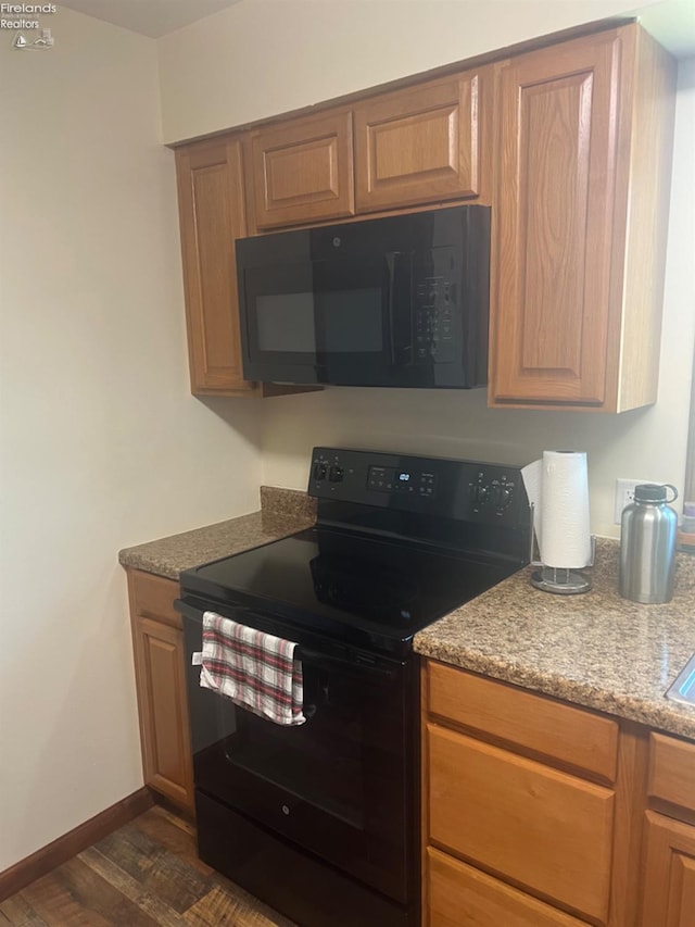 kitchen with light stone countertops, black appliances, and dark hardwood / wood-style flooring