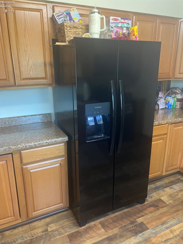 kitchen featuring black refrigerator with ice dispenser and dark hardwood / wood-style flooring