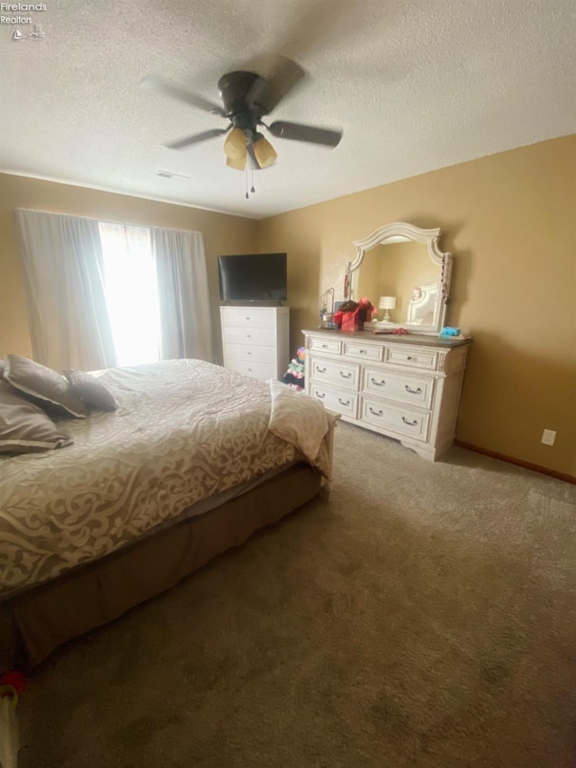 carpeted bedroom featuring ceiling fan and a textured ceiling