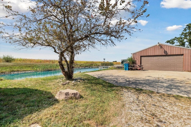 view of yard featuring a water view, an outbuilding, and a garage