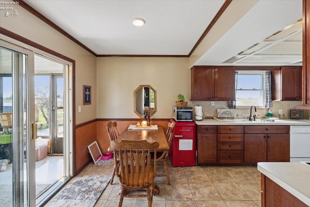 kitchen with white dishwasher, crown molding, sink, and tasteful backsplash