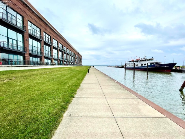 view of dock with a yard and a water view