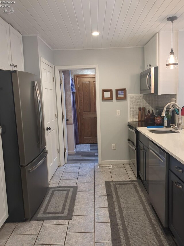 kitchen featuring white cabinets, sink, hanging light fixtures, decorative backsplash, and appliances with stainless steel finishes