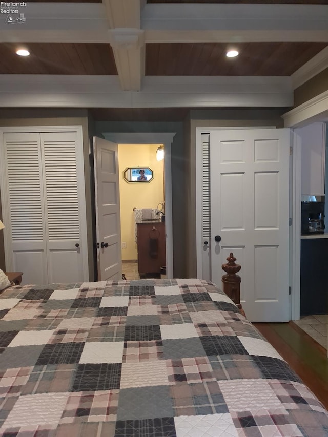 bedroom featuring beam ceiling, wooden ceiling, crown molding, and multiple closets