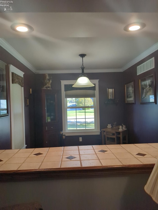 kitchen featuring tile countertops, crown molding, and hanging light fixtures