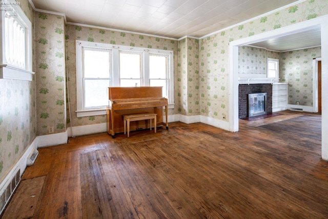 unfurnished living room featuring a brick fireplace, crown molding, and dark wood-type flooring