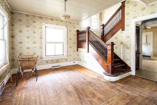 interior space with wood-type flooring, ornamental molding, and ceiling fan