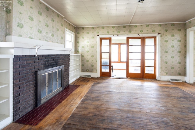 unfurnished living room with ornamental molding, a brick fireplace, a healthy amount of sunlight, and dark hardwood / wood-style flooring