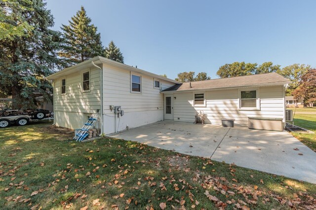 back of property with a lawn and a patio