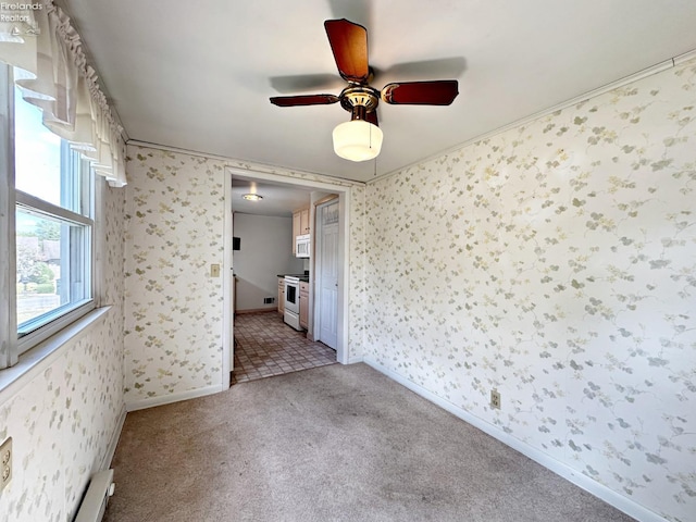 unfurnished bedroom with light carpet, a baseboard heating unit, and ceiling fan