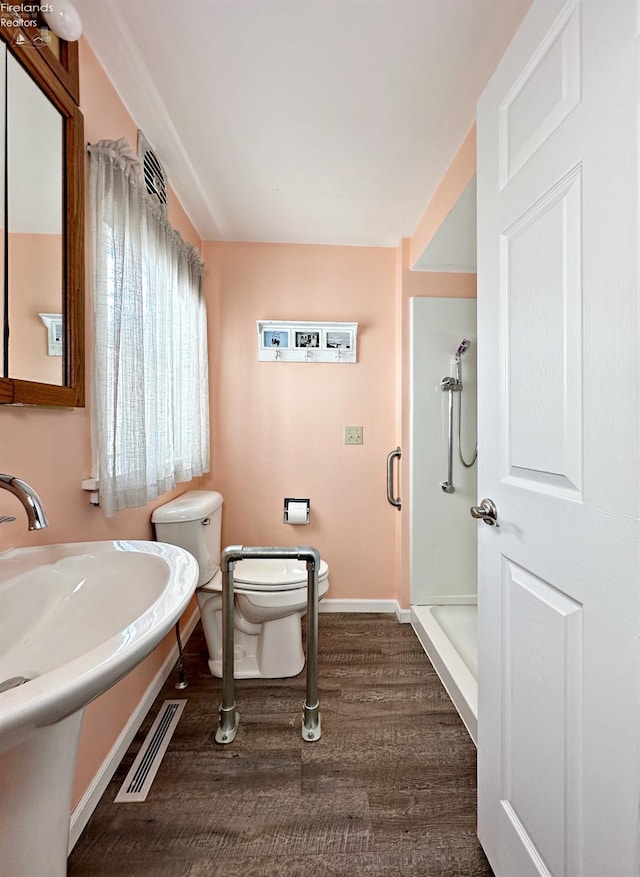 bathroom featuring walk in shower, hardwood / wood-style floors, and toilet