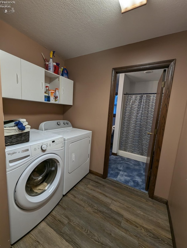 washroom with a textured ceiling, dark hardwood / wood-style flooring, washer and dryer, and cabinets