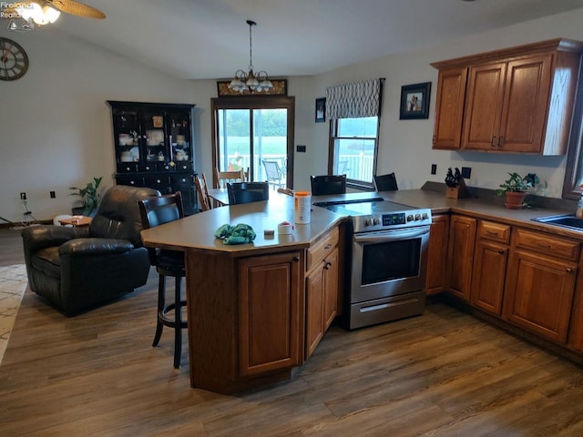 kitchen featuring a breakfast bar, kitchen peninsula, electric range, and dark hardwood / wood-style flooring