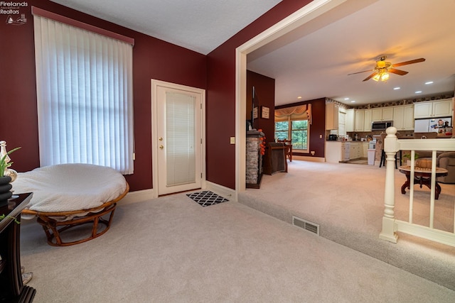 sitting room with ceiling fan and light colored carpet