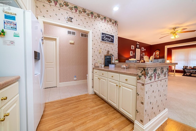 kitchen featuring kitchen peninsula, white fridge with ice dispenser, ceiling fan, and light hardwood / wood-style flooring