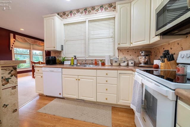 kitchen with light hardwood / wood-style floors, sink, white cabinetry, decorative backsplash, and white appliances