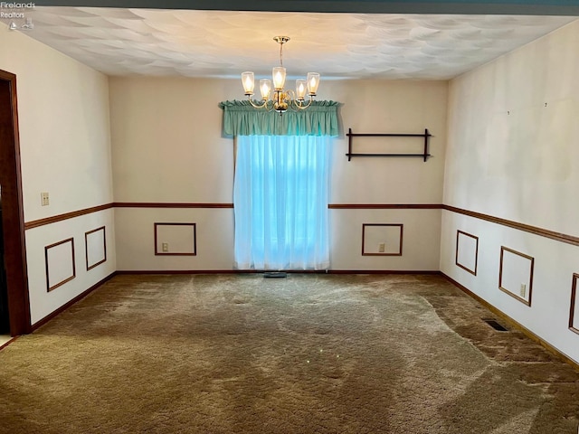 unfurnished room with carpet floors, a textured ceiling, and a chandelier