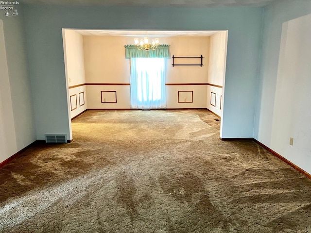 spare room with a notable chandelier and carpet