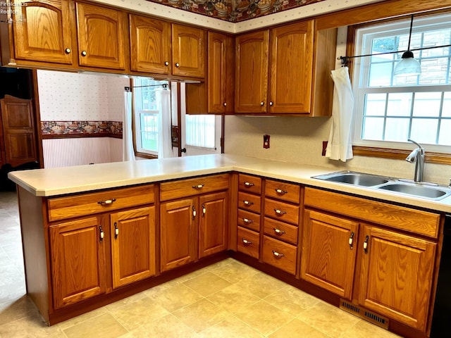 kitchen with kitchen peninsula, sink, black dishwasher, and decorative light fixtures