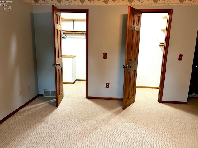 interior space featuring a walk in closet, a closet, and light colored carpet