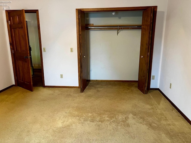 unfurnished bedroom with light colored carpet and a closet