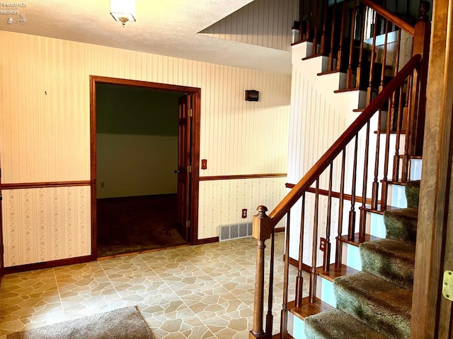 staircase featuring a textured ceiling